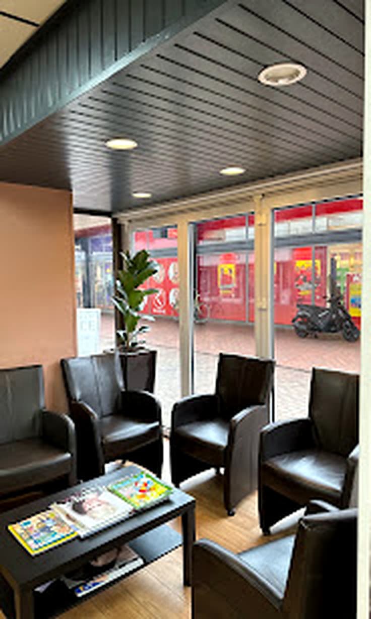 Wachthoek met zwarte leren fauteuils, een plant en tijdschriften